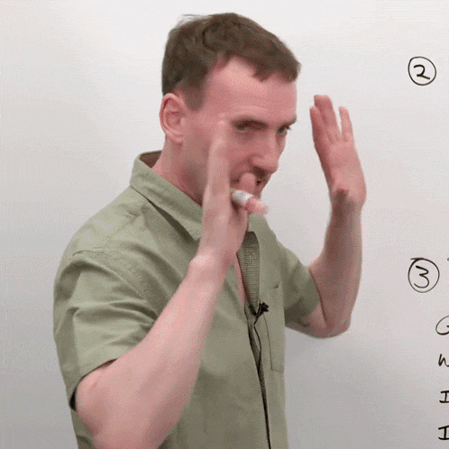 a man in a green shirt is holding a marker in his mouth