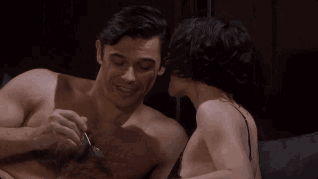 a man and woman are kissing on a bed and the woman is wearing a bra