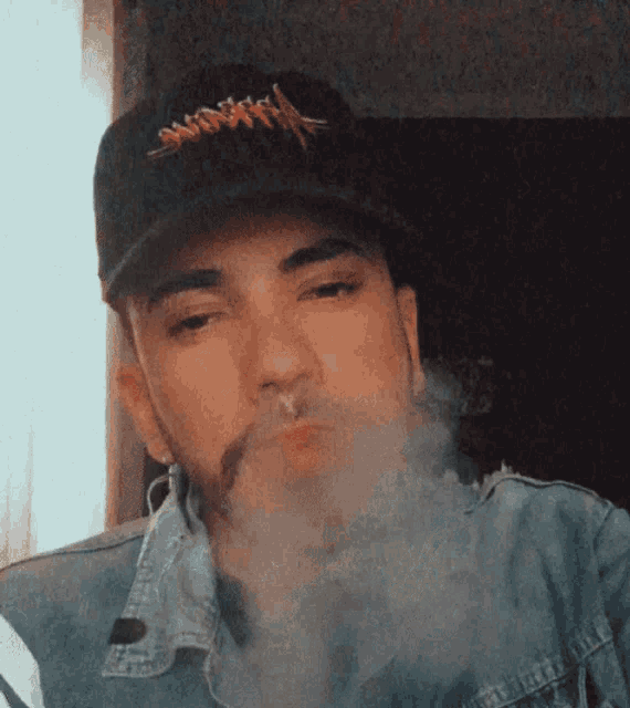 a man wearing a black hat with the word nirvana on it smoking a cigarette