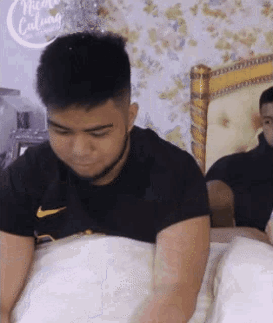 a man wearing a black nike shirt is laying in bed