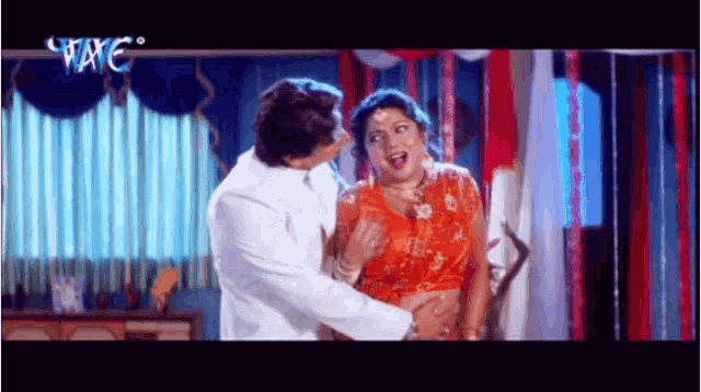 a man in a white suit is touching a woman 's belly in a scene from a movie ..