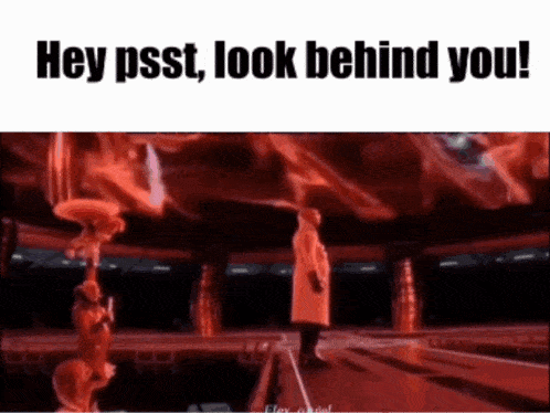 a man in a red coat is standing on a stage in front of a crowd and says hey psst look behind you .