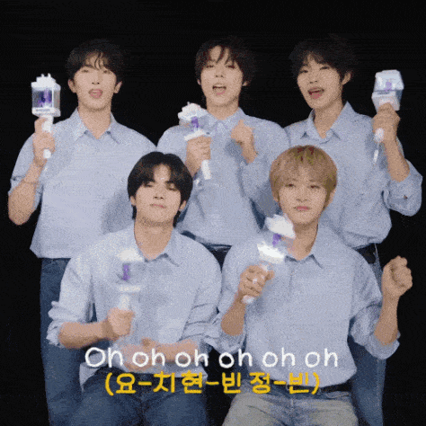 a group of young men are posing for a picture and one of them is holding a light stick that says oh oh oh oh on it