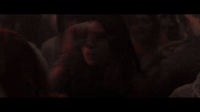 a woman in a red veil stands in a dark room
