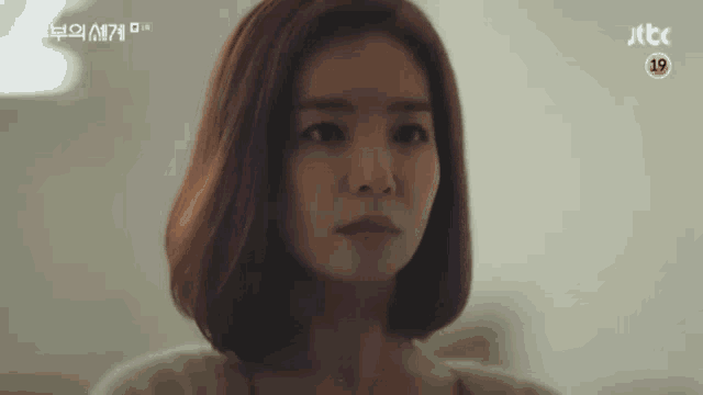 a woman with short red hair is looking at the camera in a close up of her face .