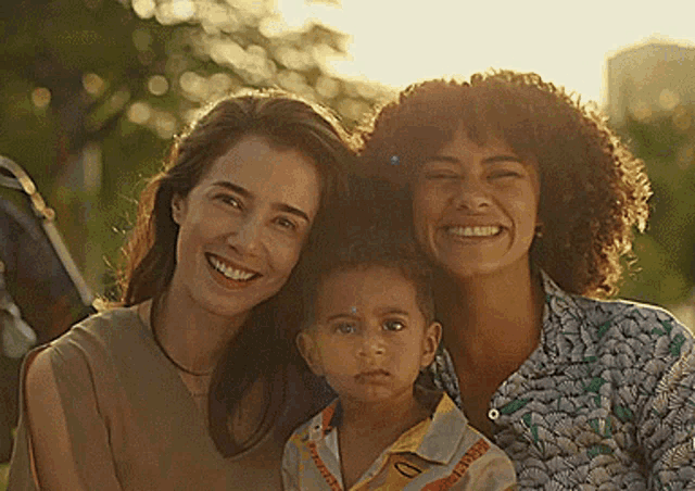 two women and a child are posing for a picture together and smiling