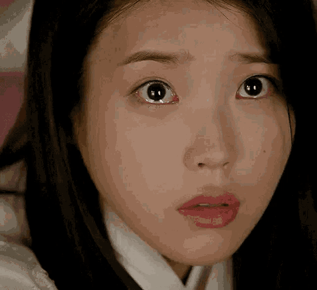 a close up of a woman 's face with a surprised look on her face and red eyes .