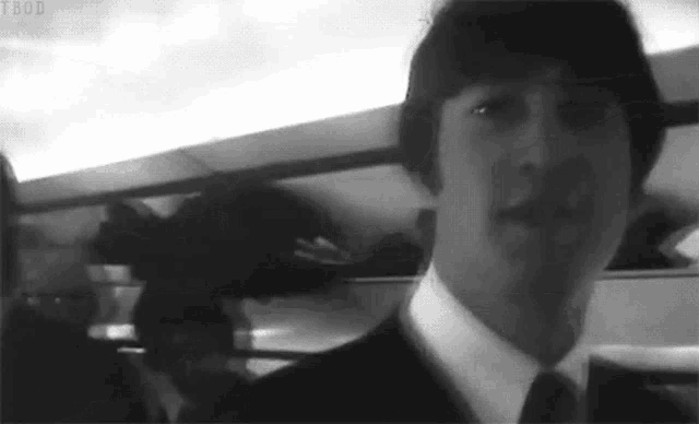 a black and white photo of a man in a suit and tie on a train .
