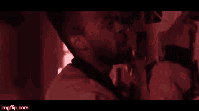 a man is standing in front of a mirror in a dark room in a red light .