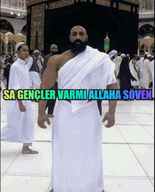 a man with a beard is standing in front of a kaaba with the words sa gencler varmi allaha soven written above him