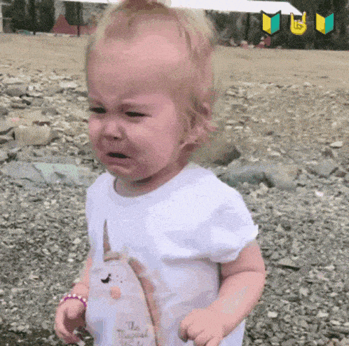 a little girl with a unicorn shirt on is crying