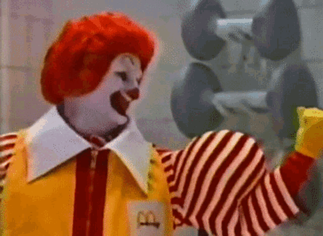 a mcdonald 's clown is holding a dumbbell in his hand