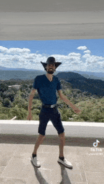 a man with a beard and a cowboy hat is dancing on a balcony .