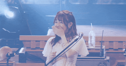 a woman singing into a microphone with a bottle of water in front of her