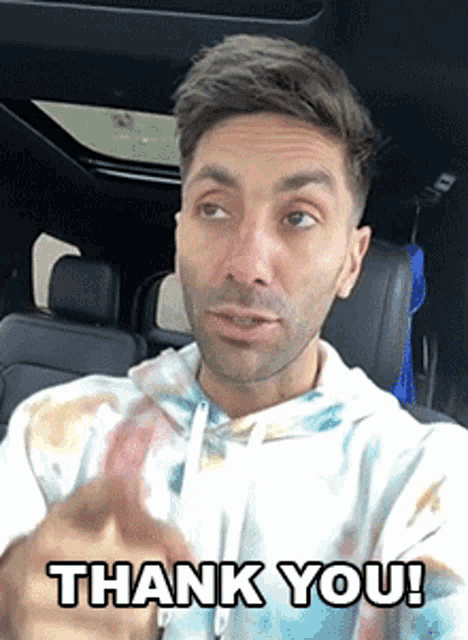 a man in a tie dye hoodie is sitting in a car and saying thank you