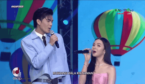 a man and a woman singing in front of hot air balloons with the words mukhang wala rin naman