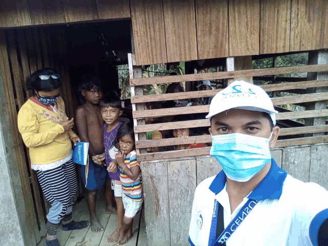 a man wearing a mask and a white hat with the letter s on it stands in front of a group of children