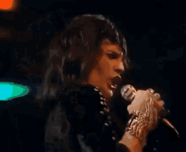a man is singing into a microphone while wearing a bracelet .