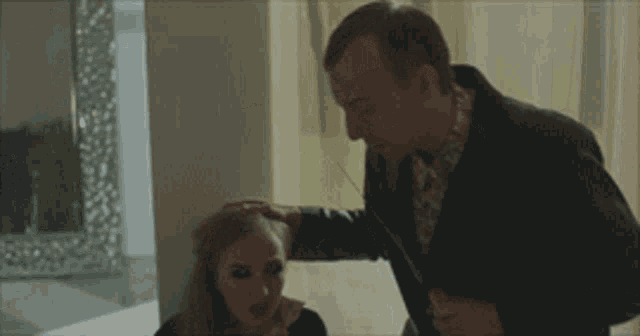 a man in a suit is touching the head of a woman