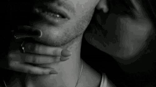 a black and white photo of a woman kissing a man on the neck .