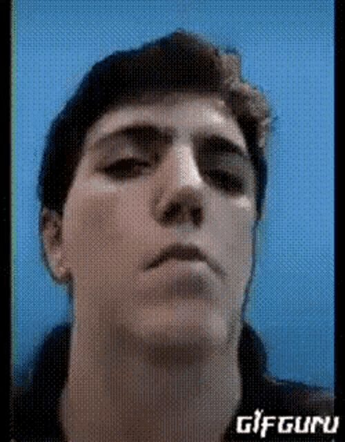 a close up of a man 's face with a blue background and the words gifguru on the bottom right