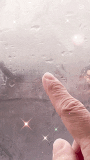a person 's finger is pointing at a rainy window .