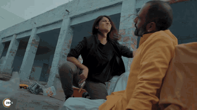 a man and a woman are fighting in front of a building that says zee5 on the bottom