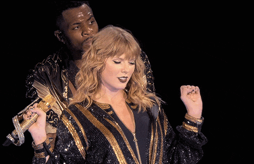 a woman in a black and gold sequined jacket holds a microphone
