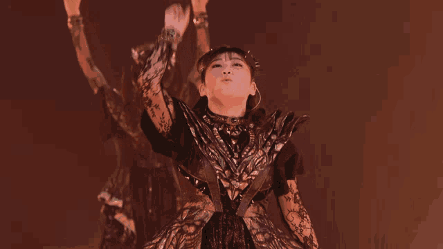 a woman in a black dress is dancing with her arms up