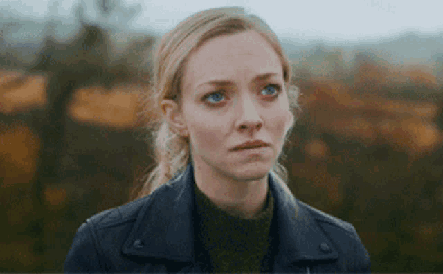 a blonde woman wearing a black leather jacket and a green sweater