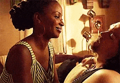a woman is sitting next to a man on a couch and they are looking at each other .
