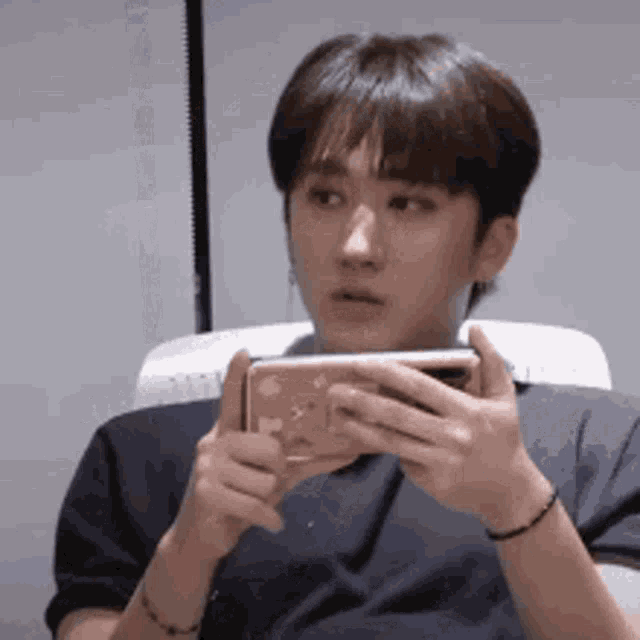 a young man is holding a cell phone in his hands .