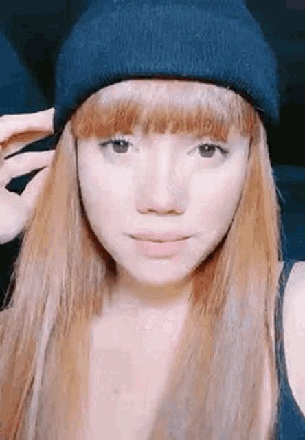 a woman with long red hair is wearing a black beanie hat .