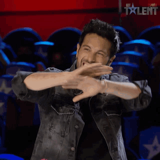 a man in a denim jacket is smiling in front of a sign that says got talent on it