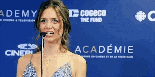a woman in a blue dress is standing in front of a microphone at an academy event