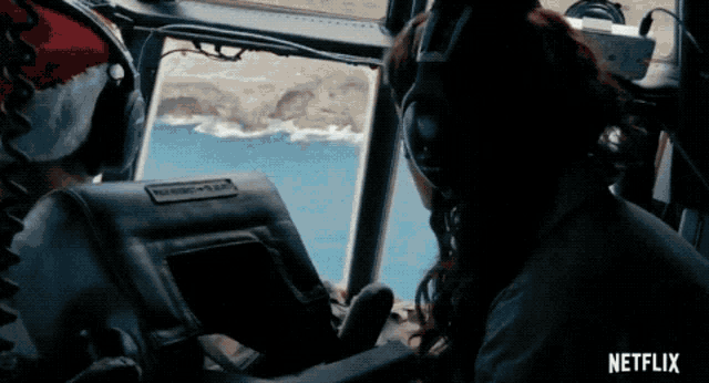 a woman wearing headphones looks out the window of a plane with netflix written on the bottom right