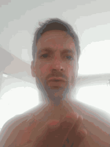 a man without a shirt is taking a selfie with his hand
