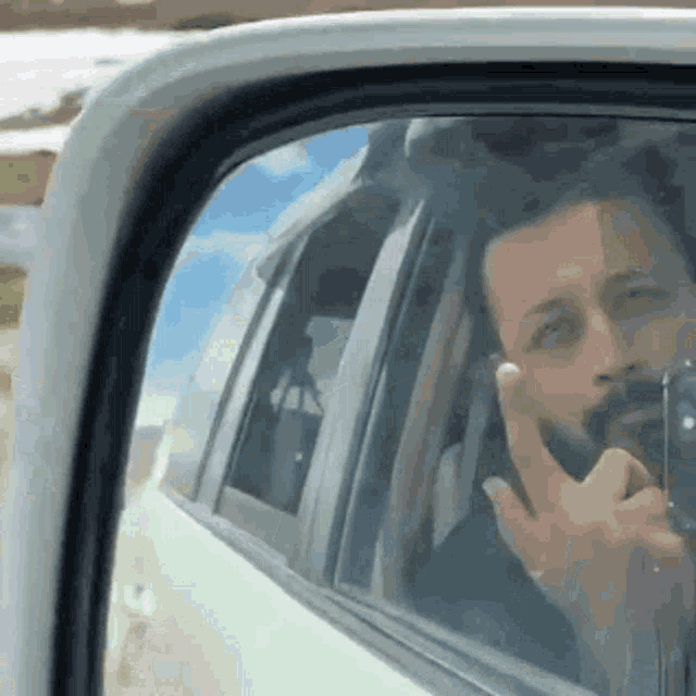 a man with a beard is taking a picture of himself in a car .