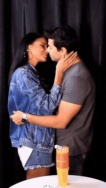 a man and a woman are kissing in front of a table