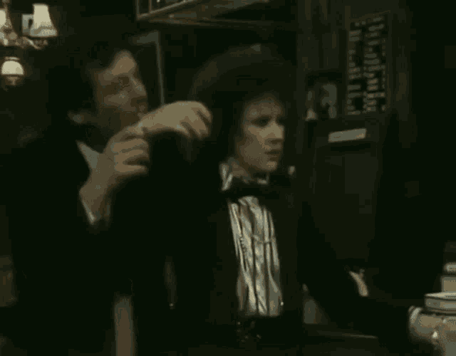 a man in a tuxedo is standing next to a woman in a tuxedo in a bar .