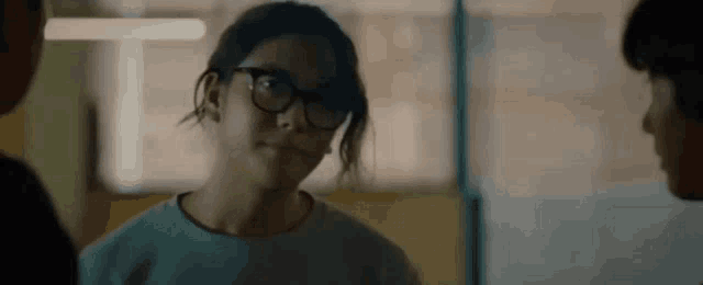 a woman wearing glasses and a blue shirt is standing in front of a group of people .