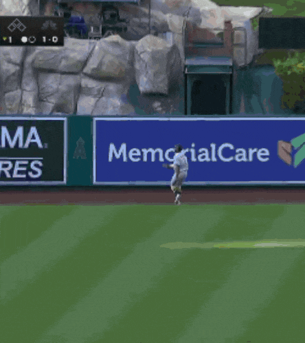 a baseball player throws a ball in front of a memorial stadium banner