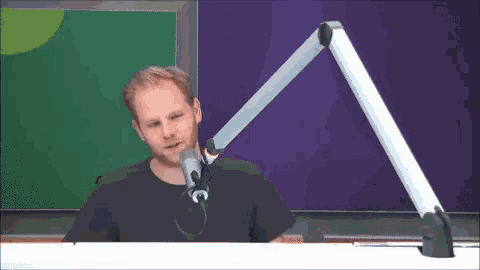 a man in a black shirt is talking into a microphone on a stand