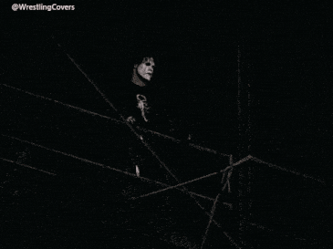a man in a black shirt with a scorpion on it stands in a dark room