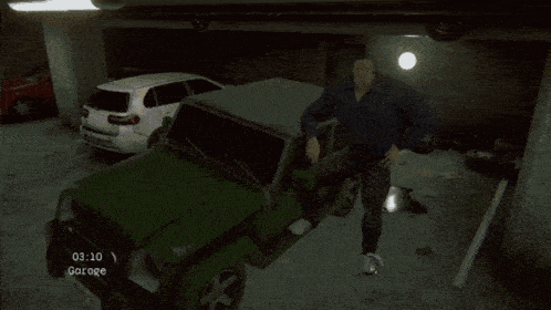 a man is standing next to a green jeep in a garage with the time of 03:10