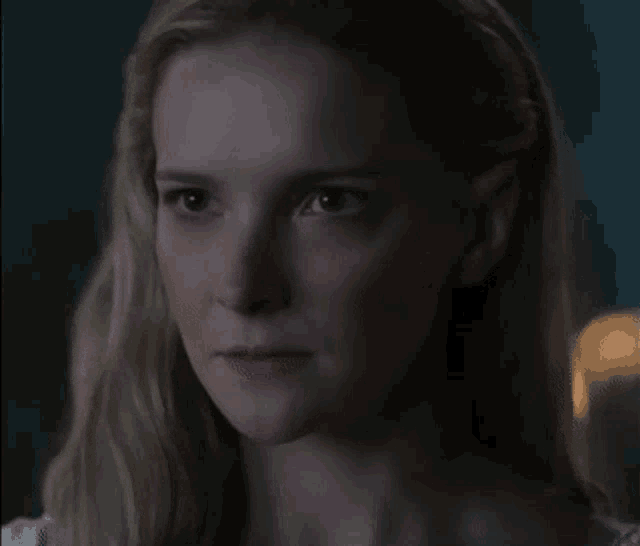 a close up of a woman 's face in a dark room with a blurred background
