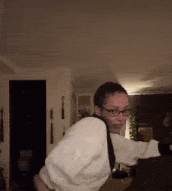 a woman wearing glasses and a white shirt is standing in a room