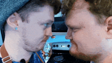two men are looking at each other with one wearing a beanie