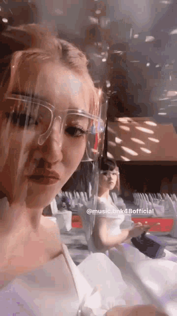 a woman wearing a face shield is taking a selfie with another woman .