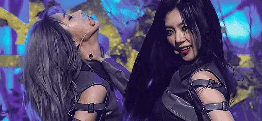 a couple of women are standing next to each other on a stage in a dark room .